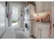 Bright laundry room with stacked washer/dryer, cabinets, sink, and access to backyard at 8927 Key West Island Way, Riverview, FL 33578