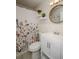 Bright bathroom features a shower with floral curtain, white vanity, and a round mirror at 9025 1St Ne St, St Petersburg, FL 33702