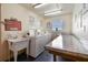 Bright laundry room featuring multiple washing machines, a utility sink, and a folding table at 1 Boca Ciega Point Blvd # 310, St Petersburg, FL 33708