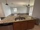 Kitchen island featuring a sink, granite countertop and open view to the living area at 10766 Standing Stone Dr, Wimauma, FL 33598