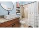 Well-lit bathroom featuring a modern vanity, stylish round mirror, and shower with a decorative curtain at 12745 Moorish Pl, Spring Hill, FL 34610