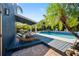 Lush backyard featuring a covered deck, luxurious pool, and tropical landscaping at 1304 Withlacoochee St, Safety Harbor, FL 34695