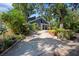 Inviting home featuring lush landscaping, a covered porch, and an expansive driveway leading to the entrance at 1304 Withlacoochee St, Safety Harbor, FL 34695