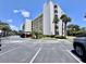 A multi-story building with parking below has palm trees and blue skies in this exterior shot at 1332 Pasadena S Ave # 208, South Pasadena, FL 33707