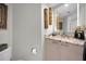 Bathroom vanity with light wood cabinets, marble countertop, decorative wall hangings, and modern mirror at 1340 Gulf Blvd # 16A, Clearwater Beach, FL 33767