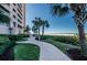 Paved path leading to a beach, surrounded by lush landscaping and palm trees at 1340 Gulf Blvd # 16A, Clearwater Beach, FL 33767