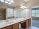 Bathroom features a long vanity with dual sinks, a large mirror, and views of the tub and bedroom at 14137 Wake Robin Dr, Brooksville, FL 34604
