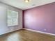Neutral bedroom with hard wood flooring, a window with blinds, and a painted accent wall at 14137 Wake Robin Dr, Brooksville, FL 34604