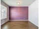 An empty bedroom featuring hard wood floors, a window with blinds, and a painted accent wall at 14137 Wake Robin Dr, Brooksville, FL 34604