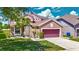 Charming two-story home featuring a landscaped front yard, palm tree, and a brick-paved driveway leading to a two-car garage at 14137 Wake Robin Dr, Brooksville, FL 34604