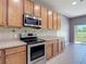 Kitchen showcasing stainless steel appliances, wood cabinets, and backyard view at 14137 Wake Robin Dr, Brooksville, FL 34604