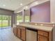 Kitchen with counter seating, stainless steel dishwasher and sink looking out to a bright living area at 14137 Wake Robin Dr, Brooksville, FL 34604