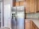 Updated kitchen features a stainless steel refrigerator, wood cabinetry, and tiled backsplash at 14137 Wake Robin Dr, Brooksville, FL 34604