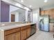 Kitchen area with stainless steel dishwasher and refrigerator overlooking the living area at 14137 Wake Robin Dr, Brooksville, FL 34604