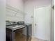 A modern laundry room boasts sleek, dark-colored appliances, wire shelving, and a convenient side door at 14137 Wake Robin Dr, Brooksville, FL 34604