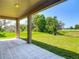 A covered patio features beige tile, columns, a ceiling light, and a view of the spacious back yard at 14137 Wake Robin Dr, Brooksville, FL 34604