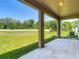 A covered patio features beige tile, columns, a ceiling light, and a view of the spacious back yard at 14137 Wake Robin Dr, Brooksville, FL 34604
