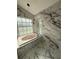 Bathroom with marble tiling featuring a soaking tub beneath a window, and arching window under construction at 14273 Nugent Circle, Spring Hill, FL 34609