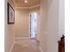 Hallway with tile flooring, neutral walls, and white trim leading to an open doorway at 15101 Kestrelglen Way, Lithia, FL 33547