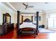 Main bedroom featuring a dark wood four poster bed, hardwood floors, and a window with shutters at 15101 Kestrelglen Way, Lithia, FL 33547