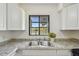 Stainless steel sink below a window with granite countertop and white cabinets at 1810 77Th N Ave, St Petersburg, FL 33702