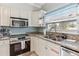 This renovated kitchen features white cabinetry, granite counters and stainless steel appliances at 1818 Indian Rocks Rd S, Largo, FL 33774