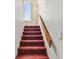 Carpeted stairway leading up to the next level with a wooden handrail and natural light at 19010 Gulf Blvd # 203, Indian Shores, FL 33785