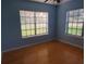 A bedroom with wood floors, blue walls, and natural light from two large windows at 2615 Southern Oaks Pl, Plant City, FL 33566