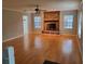 Inviting living room featuring hardwood floors, a ceiling fan, and a cozy brick fireplace, creating a warm and inviting space at 2615 Southern Oaks Pl, Plant City, FL 33566