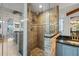 Detailed view of a glass-enclosed shower with bronze tile and a bathroom vanity with blue cabinets at 2665 Sequoia Ter # 306, Palm Harbor, FL 34683
