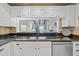 Kitchen sink area featuring stainless steel appliances, white cabinets, and granite counters at 2665 Sequoia Ter # 306, Palm Harbor, FL 34683