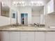 Bright bathroom featuring a double sink vanity with a granite countertop and a large mirror, with partial view of shower at 2724 Via Murano # 615, Clearwater, FL 33764