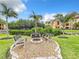 Community fire pit with bench seating surrounded by lush landscaping and palm trees at 2724 Via Murano # 615, Clearwater, FL 33764
