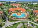Stunning aerial view of a resort-style pool with lush landscaping and vibrant orange roofs at 2724 Via Murano # 615, Clearwater, FL 33764