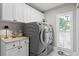 Well-lit laundry room with modern gray washer and dryer, white cabinets, and marble countertops at 2817 Seabreeze S Dr, Gulfport, FL 33707