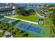 Aerial view of tennis courts with vibrant green and blue surfaces, surrounded by lush landscaping and parking at 2817 Seabreeze S Dr, Gulfport, FL 33707