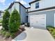 Two-story townhome features a white garage door, blue siding, and manicured landscaping at 2874 Deer Pine Trl, Land O Lakes, FL 34638