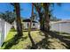 Large backyard with trees, wooden deck, manicured lawn, and white privacy fence at 3019 Park N St, St Petersburg, FL 33710
