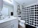 Well-lit bathroom with a black and white shower curtain, a clean white toilet, and modern fixtures at 34056 Scarlet Sage Ct, Wesley Chapel, FL 33545