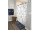 Cozy bathroom with decorative shower curtain, blue towels, and complementary brown flooring and wicker hamper at 34056 Scarlet Sage Ct, Wesley Chapel, FL 33545