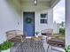 Inviting front porch features wicker seating, a decorative rug, and a charming wreath on the front door at 34056 Scarlet Sage Ct, Wesley Chapel, FL 33545