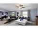 Spacious living room with a plush sofa, ceiling fan, modern decor, and ample natural light streaming through the windows at 4015 86Th E St, Palmetto, FL 34221