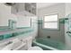 Bathroom features a tub with green tiling, a sink, and a window at 410 73Rd Ave, St Pete Beach, FL 33706