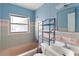 Retro bathroom featuring a pink bathtub, blue walls, and an adjacent chrome shelving unit at 410 73Rd Ave, St Pete Beach, FL 33706