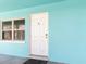 Close-up of a white front door of a turquoise home with a window, creating an inviting curb appeal at 410 73Rd Ave, St Pete Beach, FL 33706