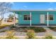 Exterior shot showcases the teal home, front porch, and neatly landscaped yard at 410 73Rd Ave, St Pete Beach, FL 33706