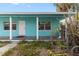A turquoise home exterior, featuring a covered porch with white support columns and the front door with number 2 at 410 73Rd Ave, St Pete Beach, FL 33706