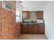 Compact kitchen with wooden cabinetry, tile backsplash, and a double basin sink at 410 73Rd Ave, St Pete Beach, FL 33706