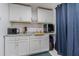 Clean kitchenette features white cabinets, granite countertops, microwave, mini-fridge and sink at 4150 Woodsville Dr, New Port Richey, FL 34652