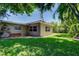Exterior view of the home's backyard with a lush green lawn and mature trees at 4174 14Th Ne Ln, St Petersburg, FL 33703